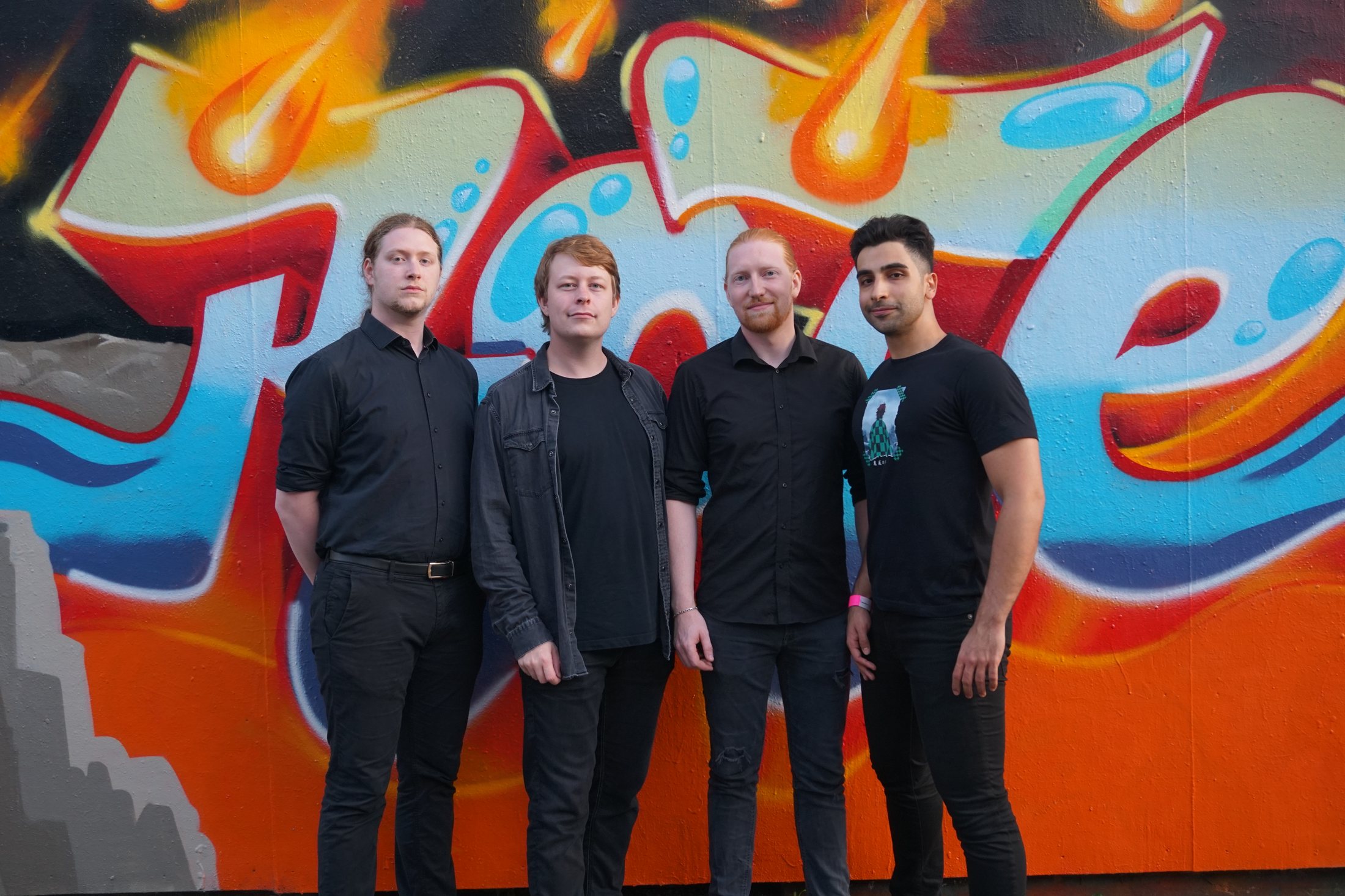 Tidestone band standing in front of colorful graffiti